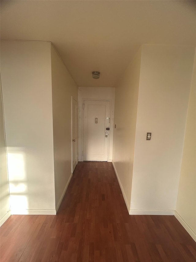 corridor with baseboards and wood finished floors