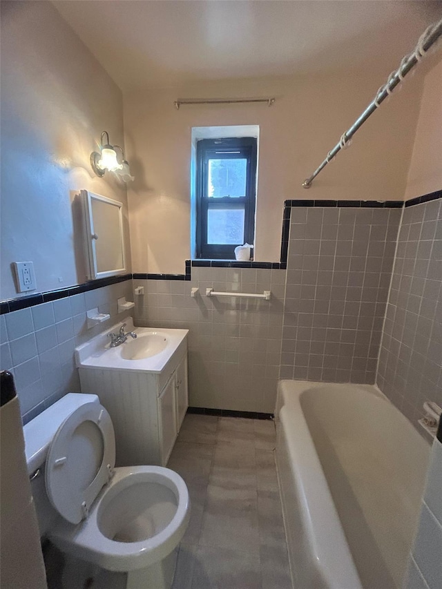 full bathroom with tile walls, toilet, shower / tub combination, wainscoting, and vanity