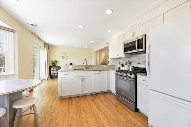118 Paquatuck Ave, East Moriches, NY 11940 - kitchen with stainless steel appliances, a sink, visible vents, white cabinets, and a peninsula