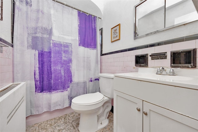 full bathroom with a wainscoted wall, toilet, vanity, shower / bath combination with curtain, and tile walls