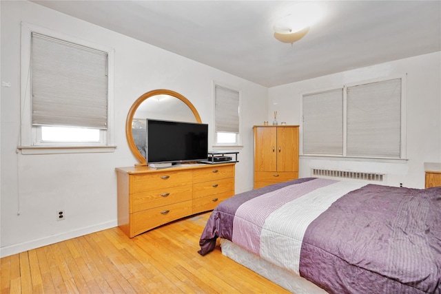 bedroom featuring light wood finished floors, radiator, and baseboards