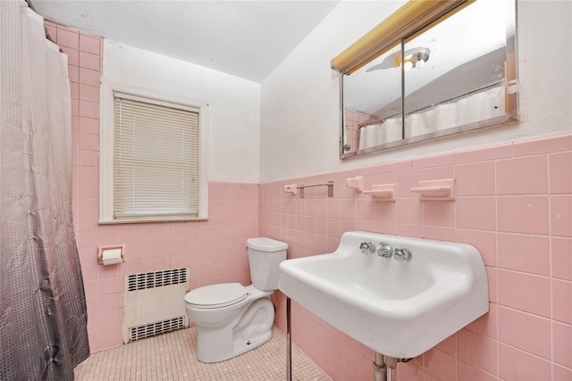 full bath with a wainscoted wall, toilet, radiator, tile walls, and tile patterned flooring