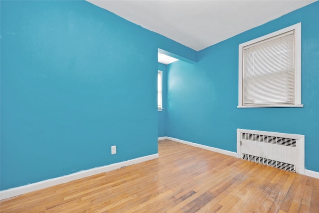 spare room featuring radiator, baseboards, and hardwood / wood-style flooring