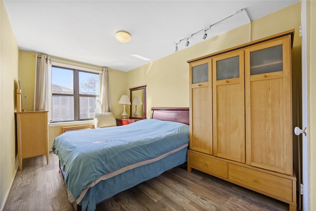 bedroom with wood finished floors and rail lighting