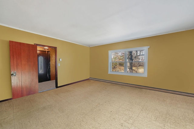 empty room featuring tile patterned floors, baseboards, and crown molding