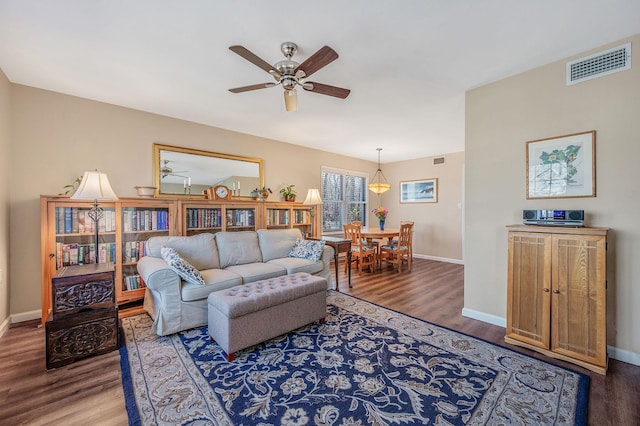 living area with wood finished floors, visible vents, and baseboards