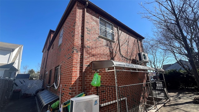 view of home's exterior featuring brick siding, cooling unit, fence, and ac unit