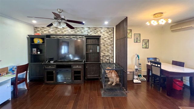 living room with a wall mounted air conditioner, wood finished floors, ornamental molding, and a ceiling fan