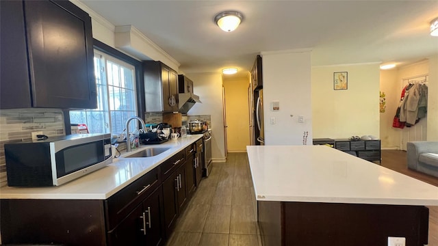 kitchen featuring tasteful backsplash, a kitchen island, light countertops, stainless steel appliances, and a sink