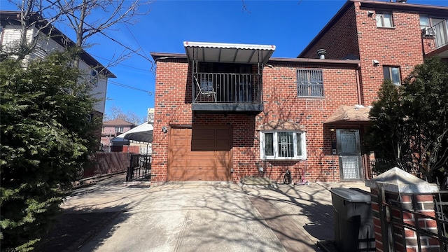 rear view of property featuring brick siding, concrete driveway, an attached garage, and fence