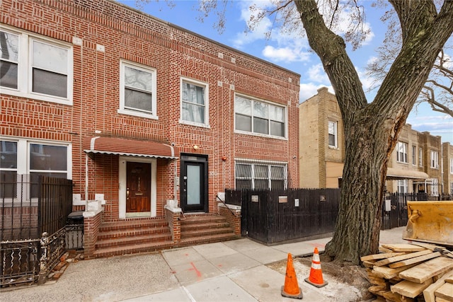 townhome / multi-family property featuring brick siding and fence