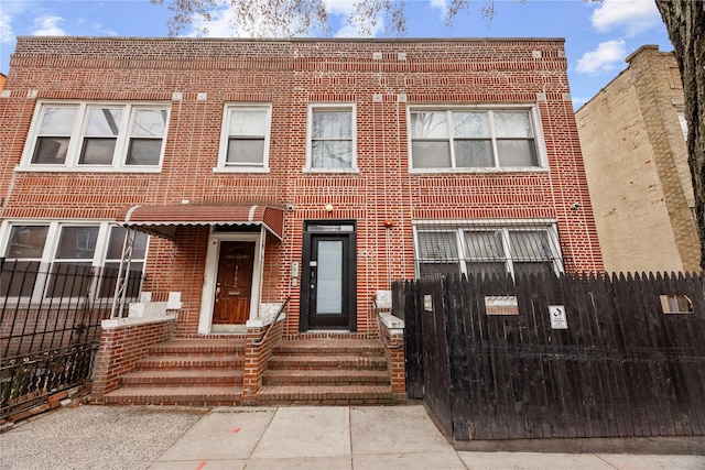 townhome / multi-family property with brick siding and fence