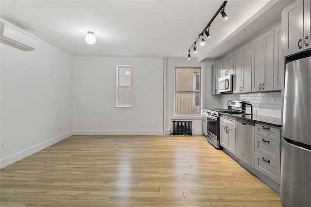 kitchen with light wood finished floors, tasteful backsplash, gray cabinets, appliances with stainless steel finishes, and a wall mounted AC