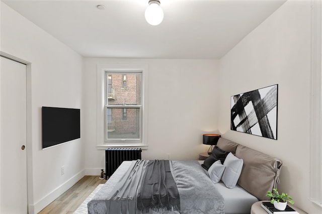bedroom with light wood-type flooring, baseboards, and radiator