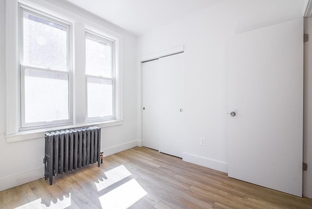 empty room with radiator, baseboards, and wood finished floors
