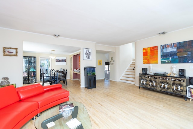 living room with visible vents, wood finished floors, stairs, and crown molding