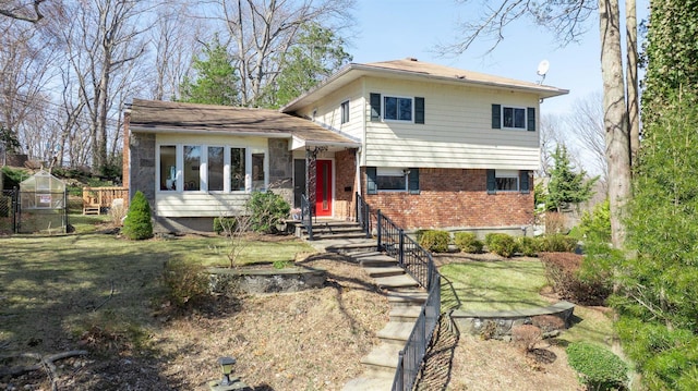 tri-level home with brick siding, a front lawn, and fence