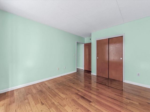 unfurnished bedroom with a closet, baseboards, and wood finished floors