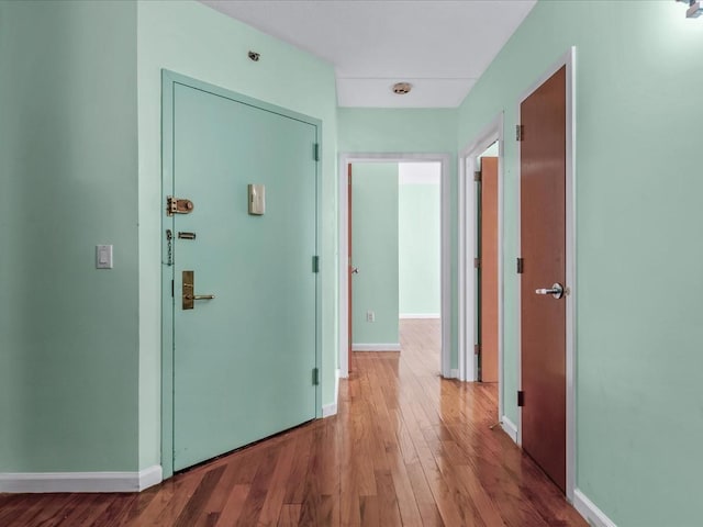 corridor featuring wood finished floors and baseboards