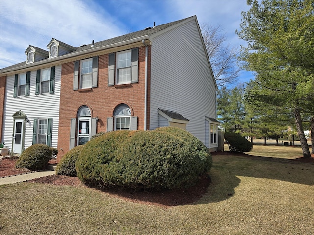 view of side of home with a lawn and brick siding