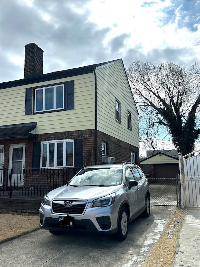 view of home's exterior with brick siding, fence, a chimney, a garage, and a gate