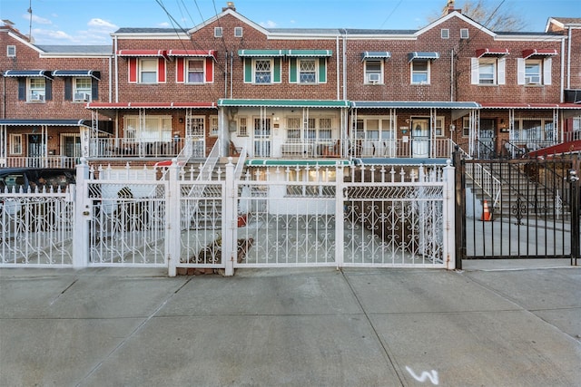 multi unit property with brick siding, a fenced front yard, and a gate