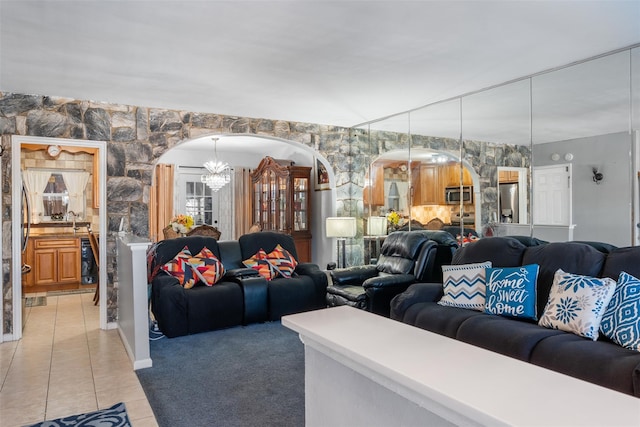 living room featuring light tile patterned flooring, arched walkways, light carpet, and beverage cooler