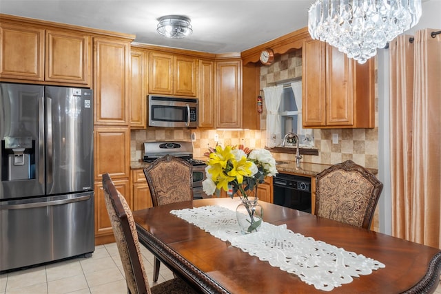 kitchen featuring light tile patterned floors, a sink, decorative backsplash, appliances with stainless steel finishes, and a chandelier