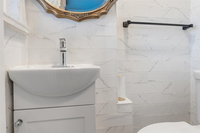 bathroom featuring toilet, vanity, and tile walls