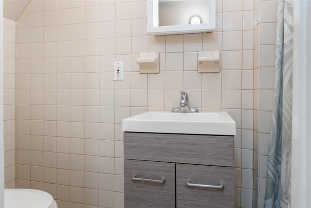 full bath with backsplash, curtained shower, toilet, vanity, and tile walls