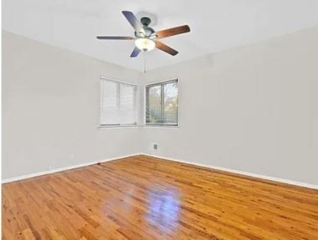 empty room with baseboards, a ceiling fan, and wood finished floors