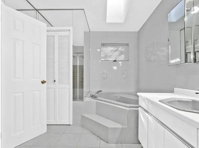 bathroom with vanity, tile patterned floors, a bath, and tile walls