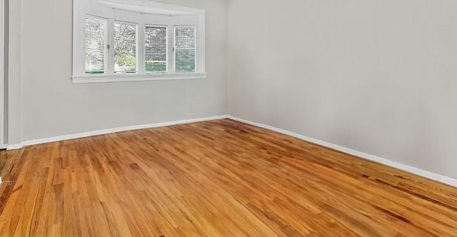 empty room with light wood-type flooring and baseboards