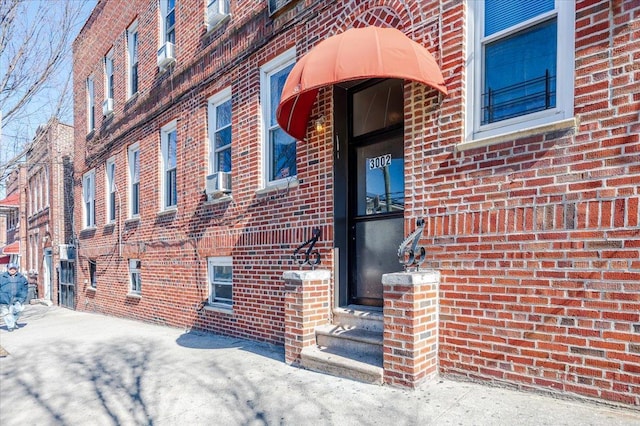 entrance to property featuring brick siding and cooling unit