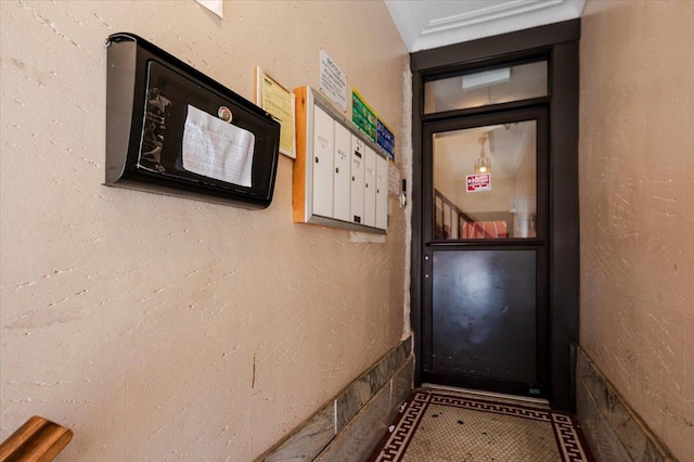 doorway to outside with mail area and a textured wall