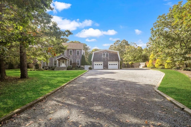 colonial-style house featuring a garage, an outbuilding, and a front yard