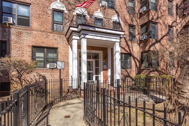 entrance to property featuring brick siding and fence