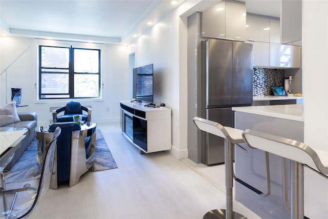 kitchen featuring freestanding refrigerator, decorative backsplash, light countertops, modern cabinets, and light wood-type flooring