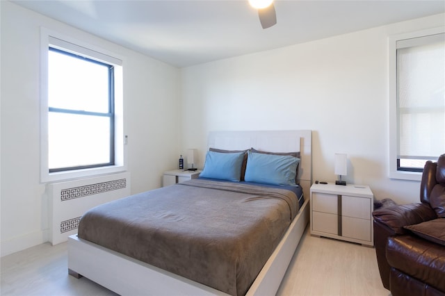 bedroom featuring radiator, light wood-type flooring, and ceiling fan