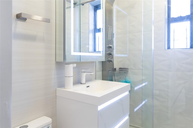 bathroom with toilet, tasteful backsplash, tile walls, a shower stall, and vanity