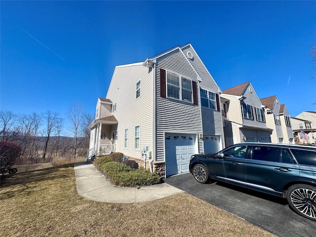 view of side of property with aphalt driveway, a residential view, and an attached garage