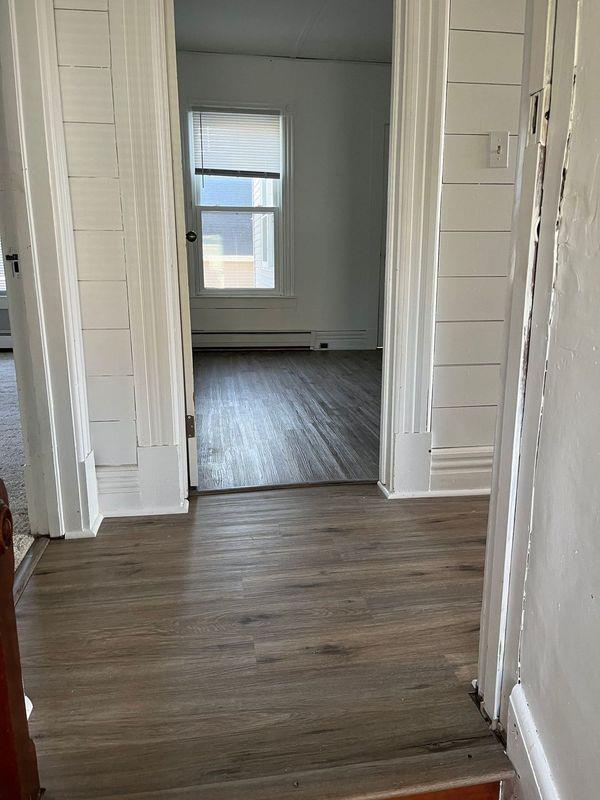 hallway featuring a baseboard heating unit and dark wood-type flooring
