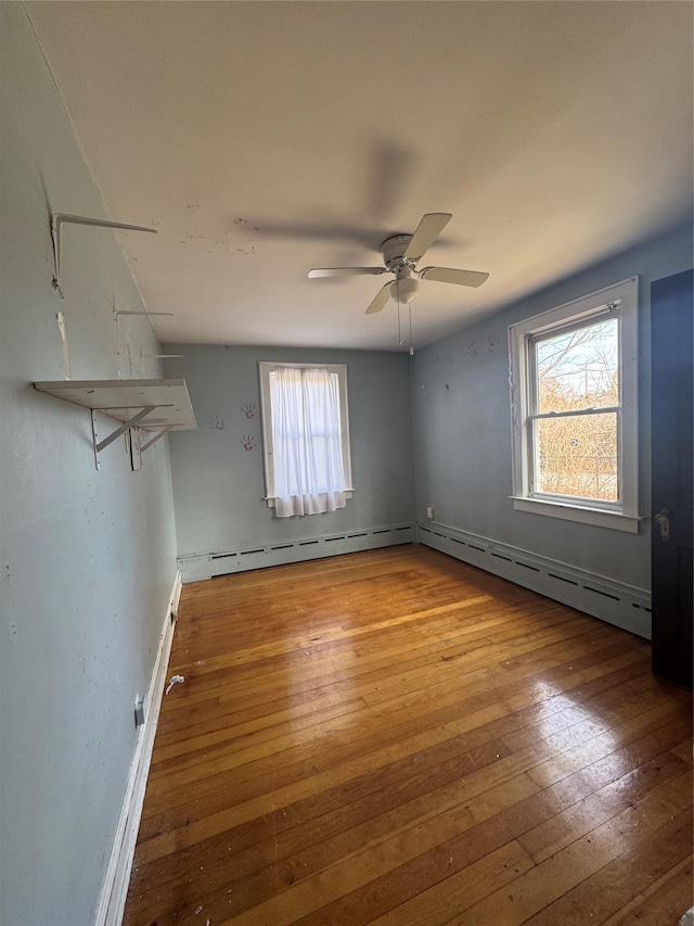 unfurnished room with a baseboard radiator, wood-type flooring, and a ceiling fan