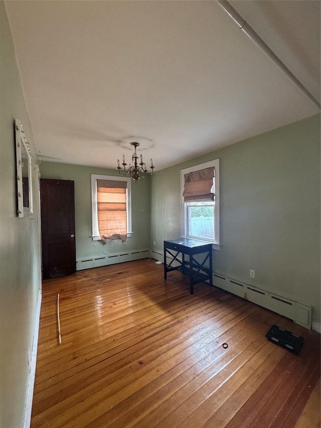 unfurnished dining area with baseboard heating, a notable chandelier, and wood-type flooring