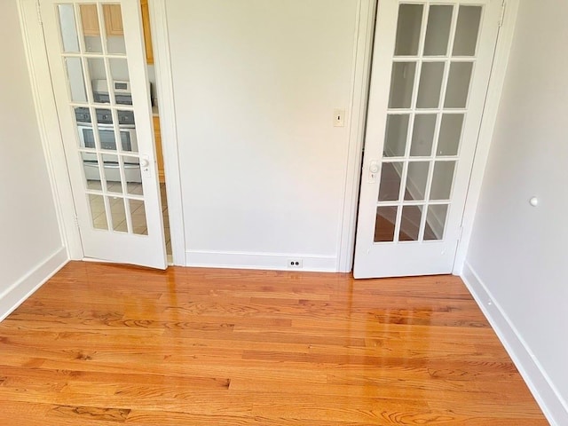 spare room with baseboards and light wood-type flooring