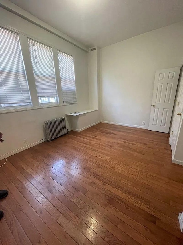 23-12 Broadway, Astoria, NY 11106 - empty room featuring visible vents, radiator, baseboards, and wood-type flooring