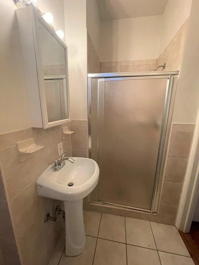 23-12 Broadway, Astoria, NY 11106 - bathroom with tile patterned floors, tile walls, a shower stall, and a sink