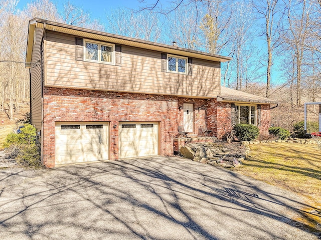 colonial-style house featuring brick siding, an attached garage, and aphalt driveway