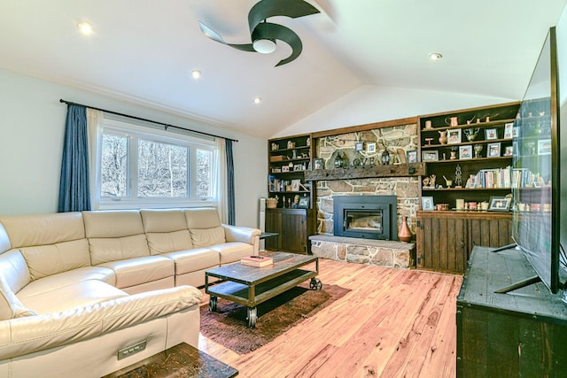 living area with a fireplace, wood finished floors, a ceiling fan, and vaulted ceiling