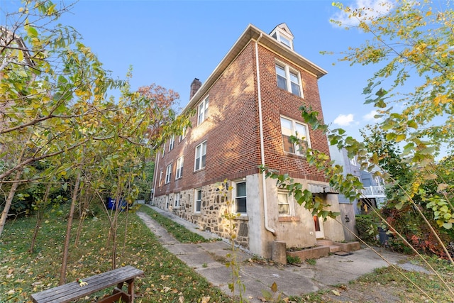 view of side of home featuring brick siding and a chimney